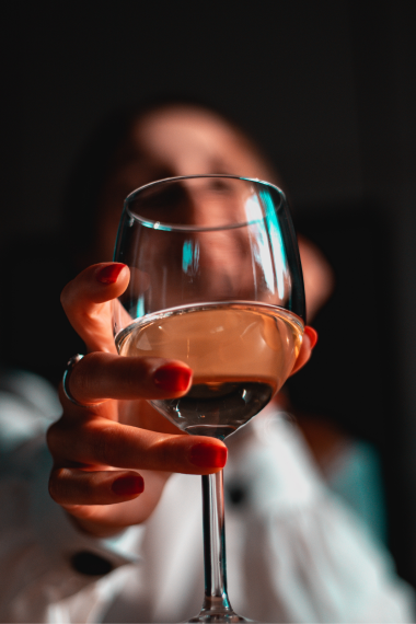 A glass of white wine in the hand of a satisfied customer